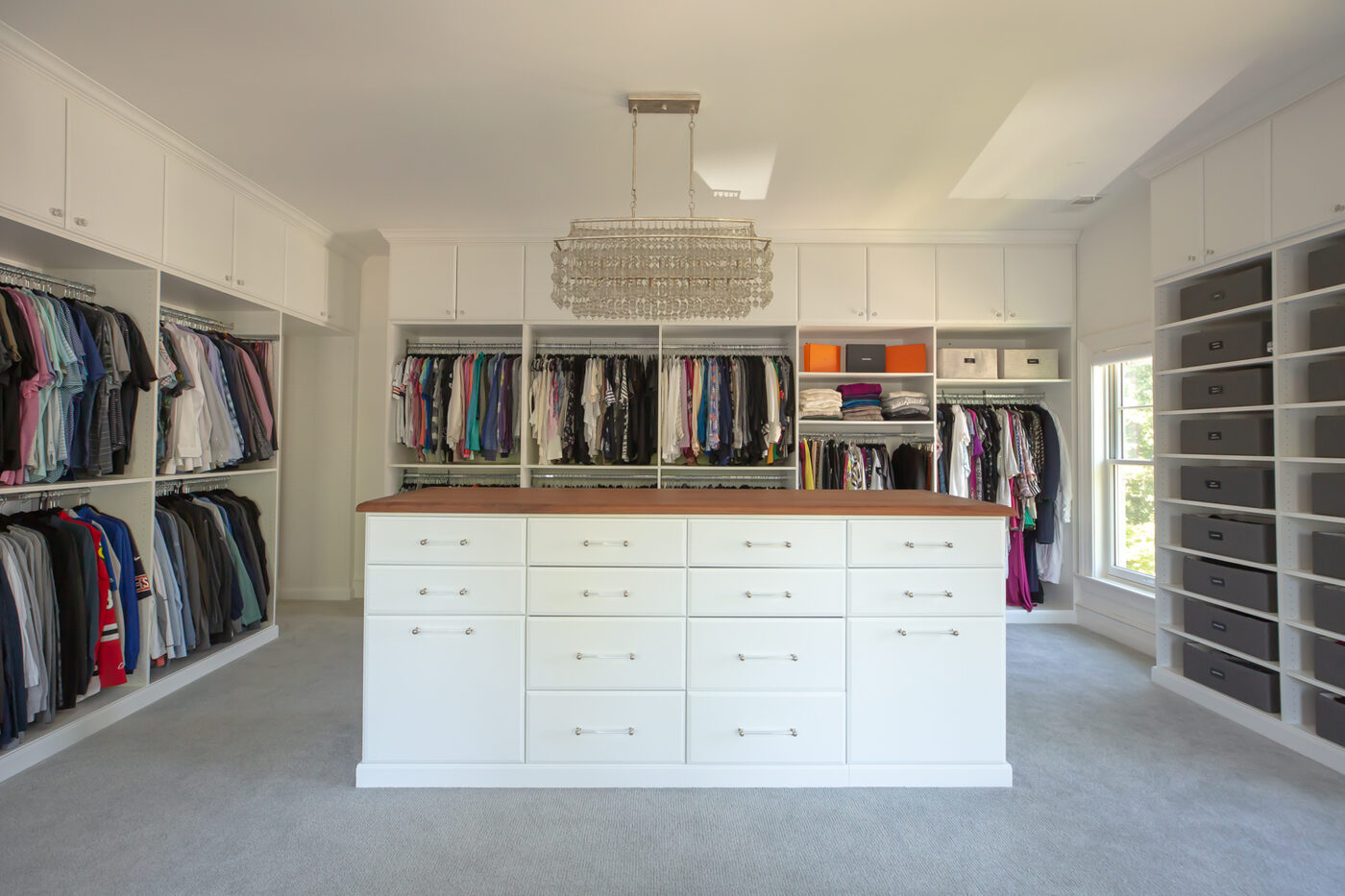 Walk-in closet with white island and chandelier